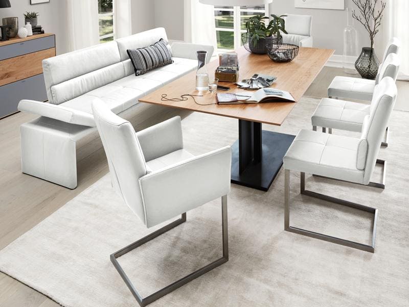 Helles, modernes Esszimmer mit einem Holztisch und drumherum weißen Essstühlen aus Leder