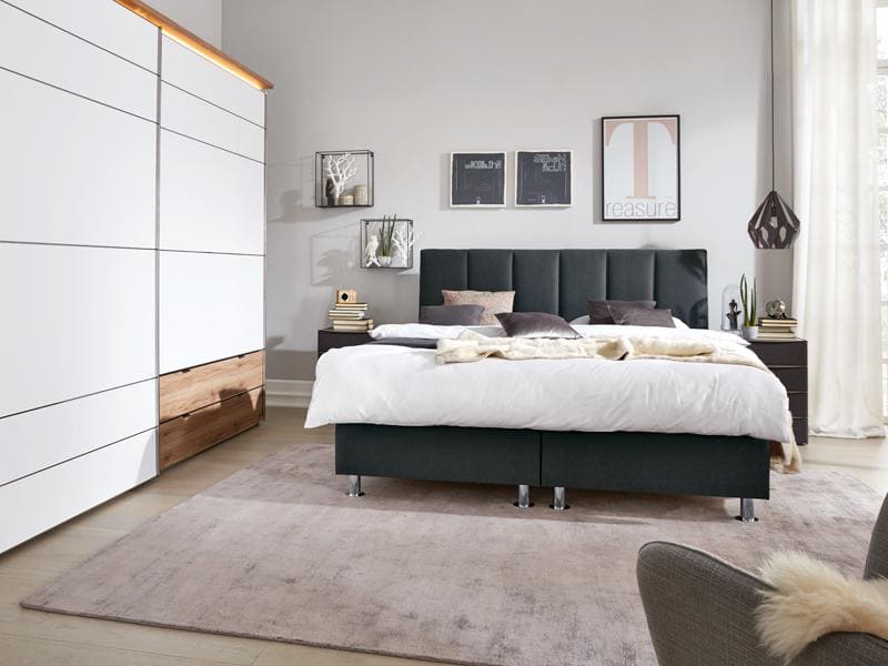 Schwarzes Bett in eingerichtetem Schlafzimmer