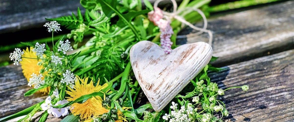 Holzherz auf gepflückten Blumen platziert