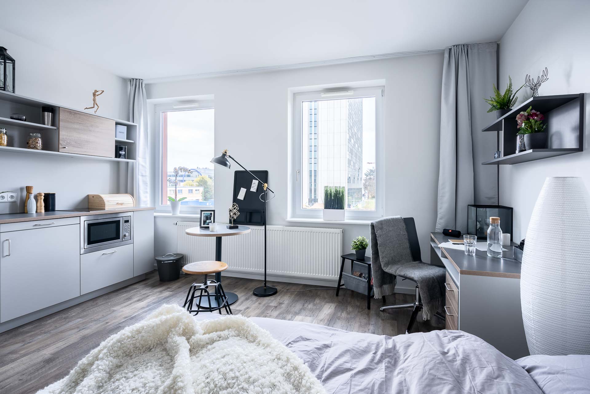 1 Zimmerwohnung in hellen Farben, mit einer kleinen Küchenzeile, einem Bett und einem Schreibtisch