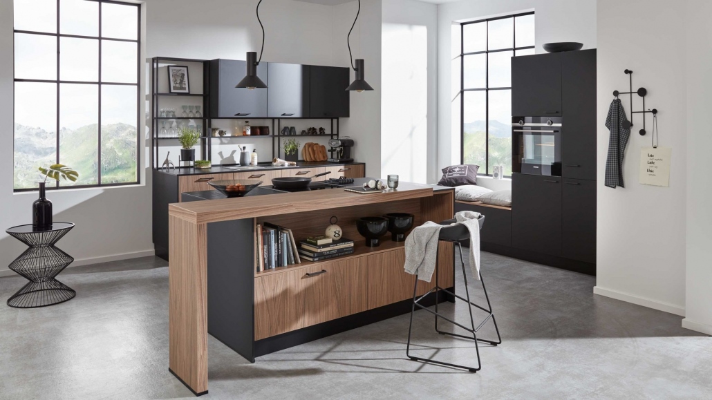 Schmale Kücheninsel in Schwarz mit Holzdetails, davor ein Barhocker
