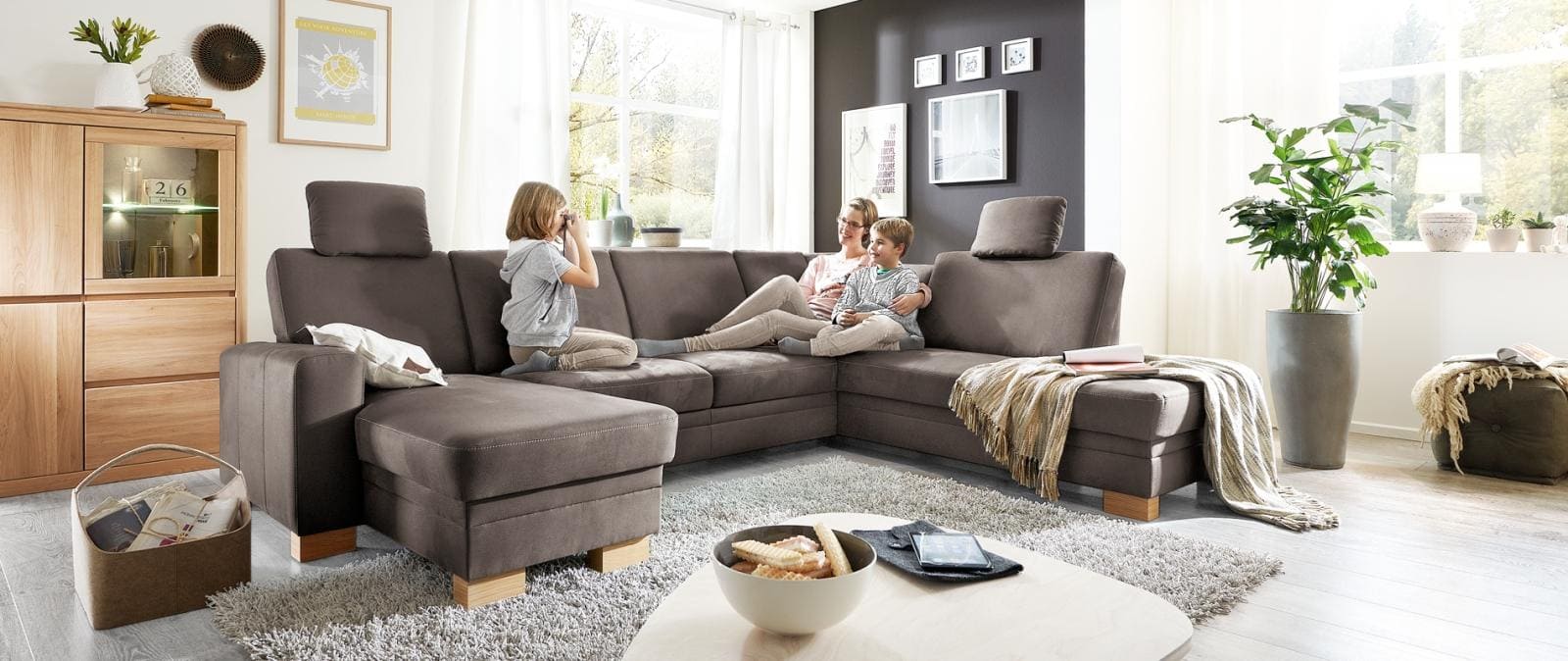 Taupe farbiges Sofa, mit Mutter und zwei Kindern darauf