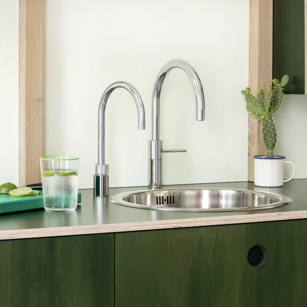 Quooker in Silber an einer silbernen Spüle einer grünen Küche
